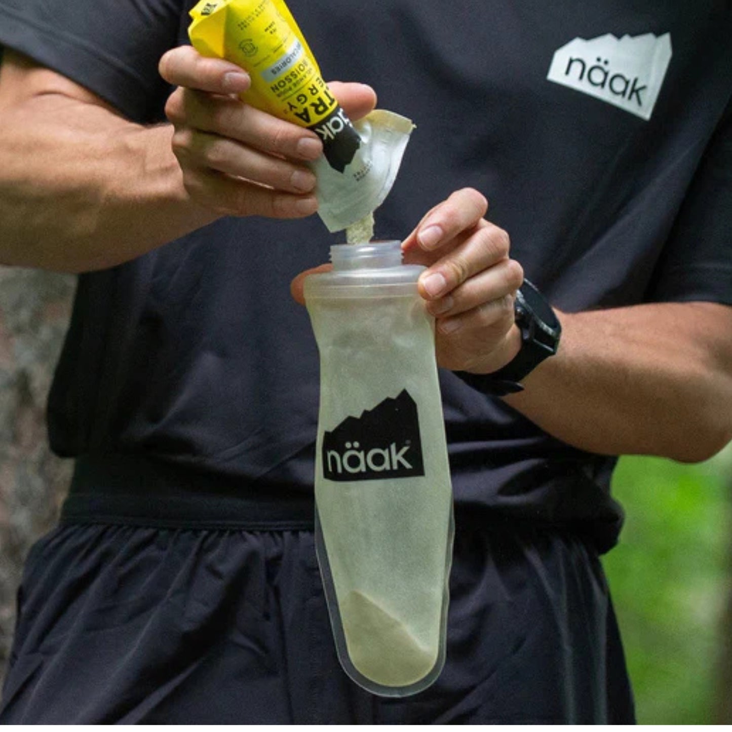 Person pouring a supplement into a Naák branded container outdoors.