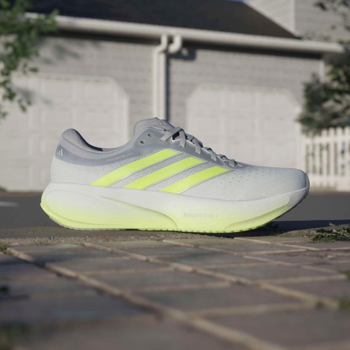 Gray and yellow adidas running shoe on a pavement with a blurred background