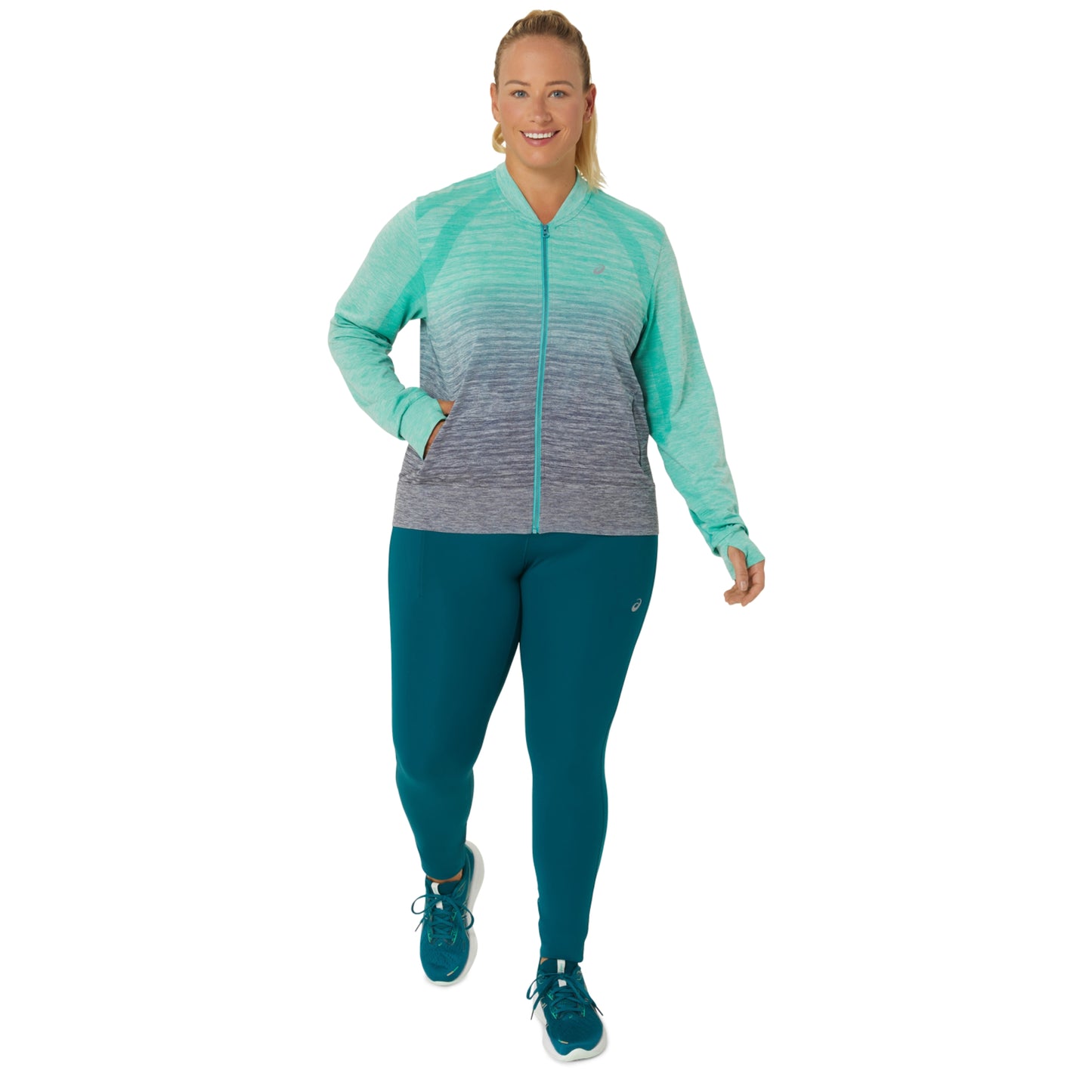 Woman wearing a teal and gray athletic jacket with matching leggings on a white background