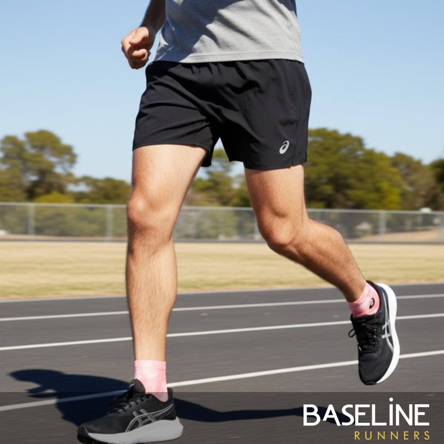 Person running on a track wearing black shorts with a visible brand logo.