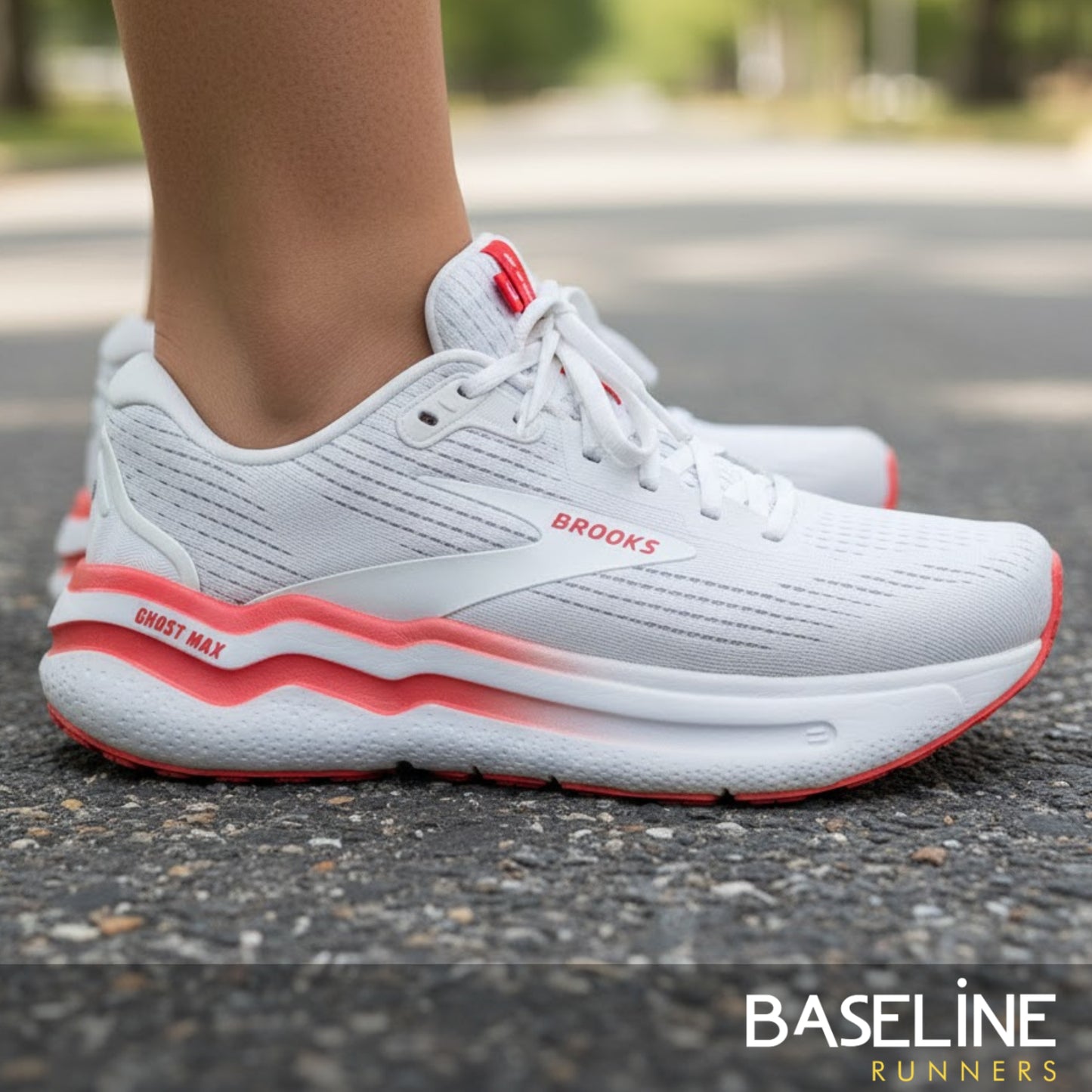 White running shoes with red accents on a road, featuring the Brooks brand.