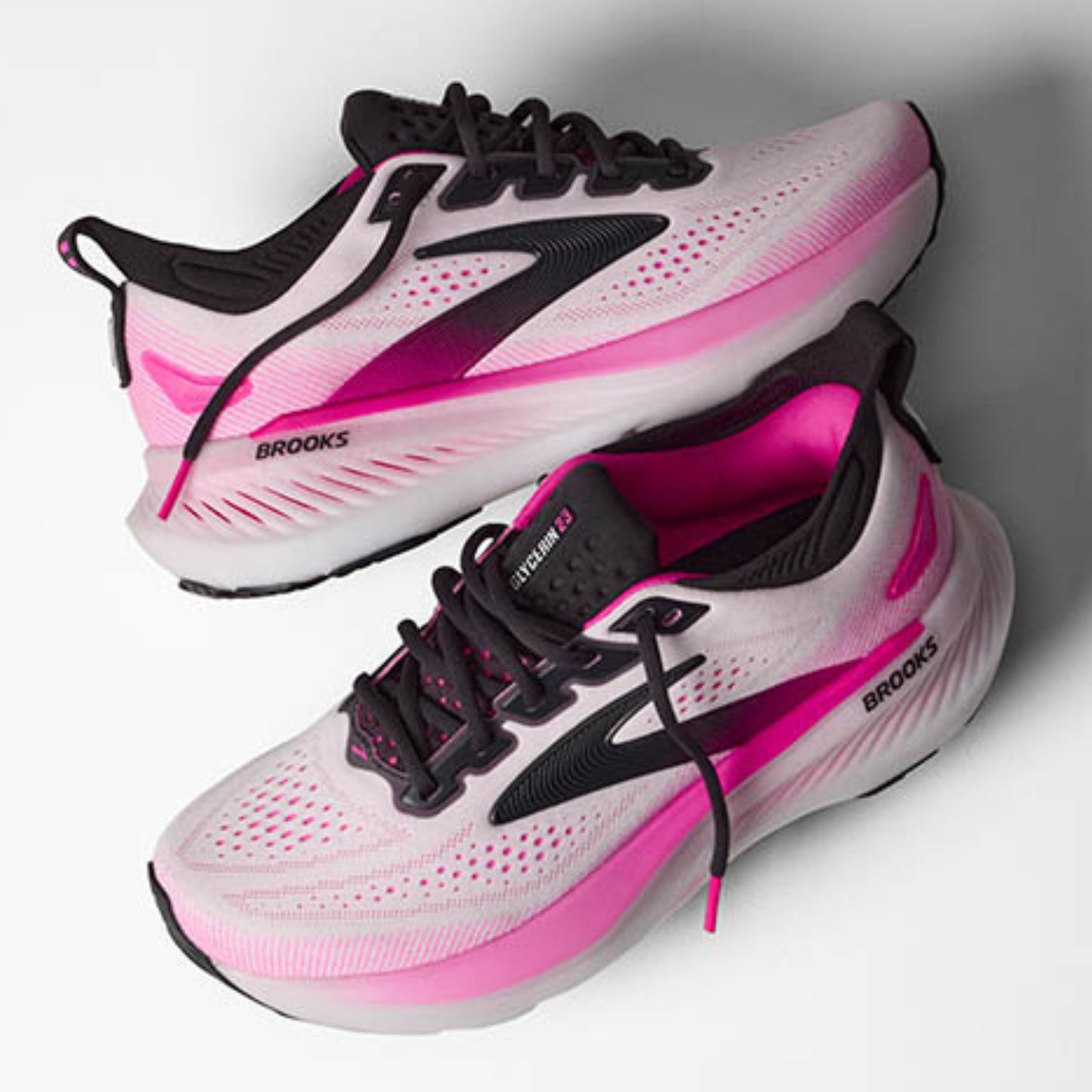 Pink and white Brooks running shoes with black laces on a gray background