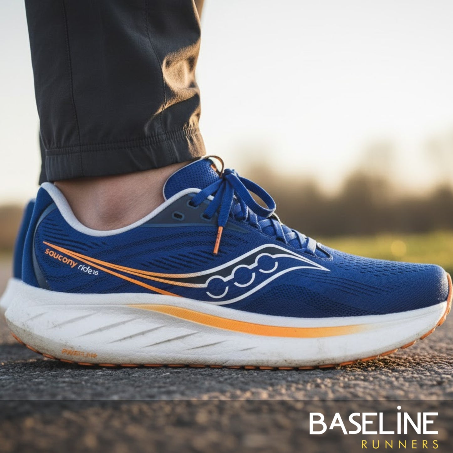 Blue running shoe with orange accents on a blurred outdoor background