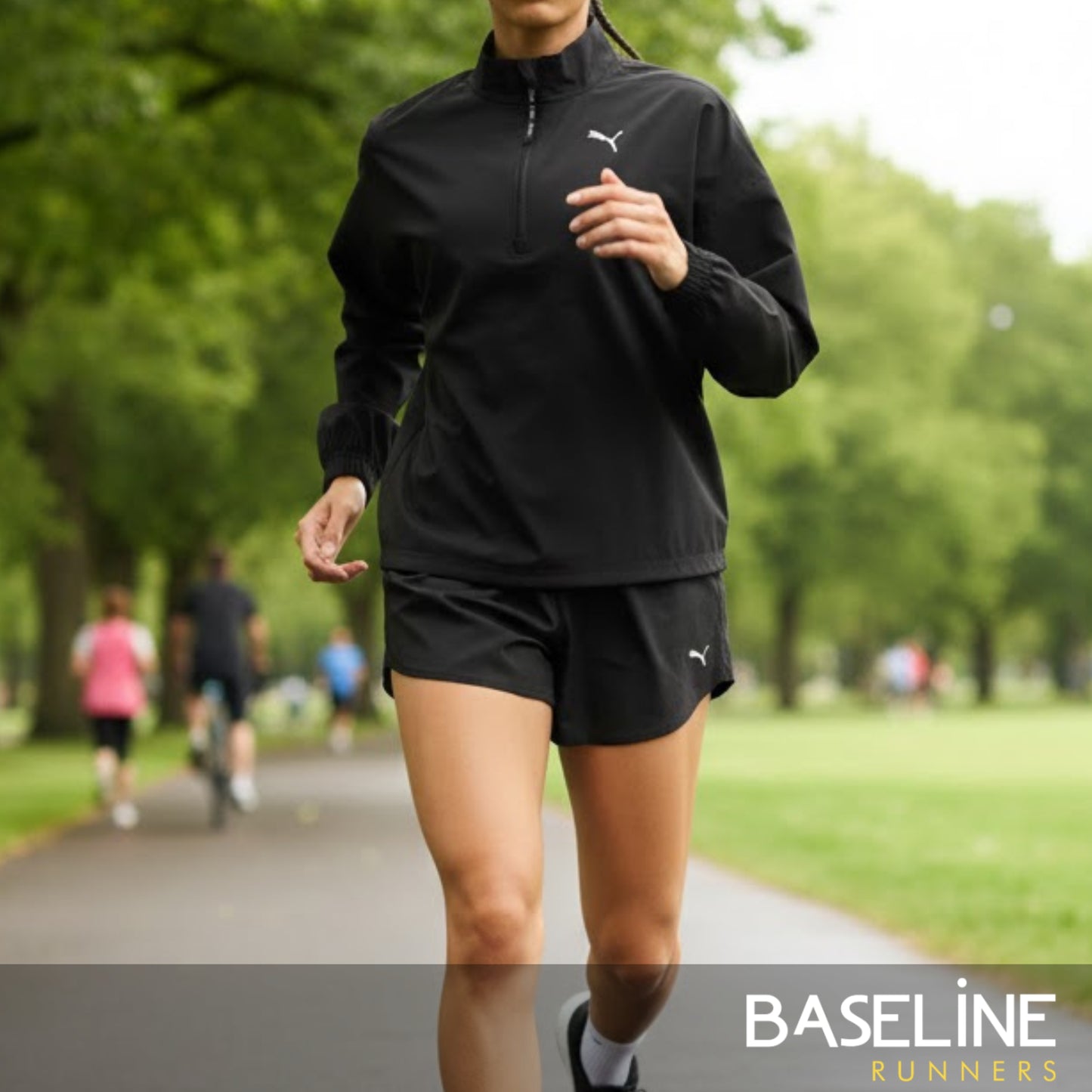 Person running in a park wearing a black Puma jacket and shorts.