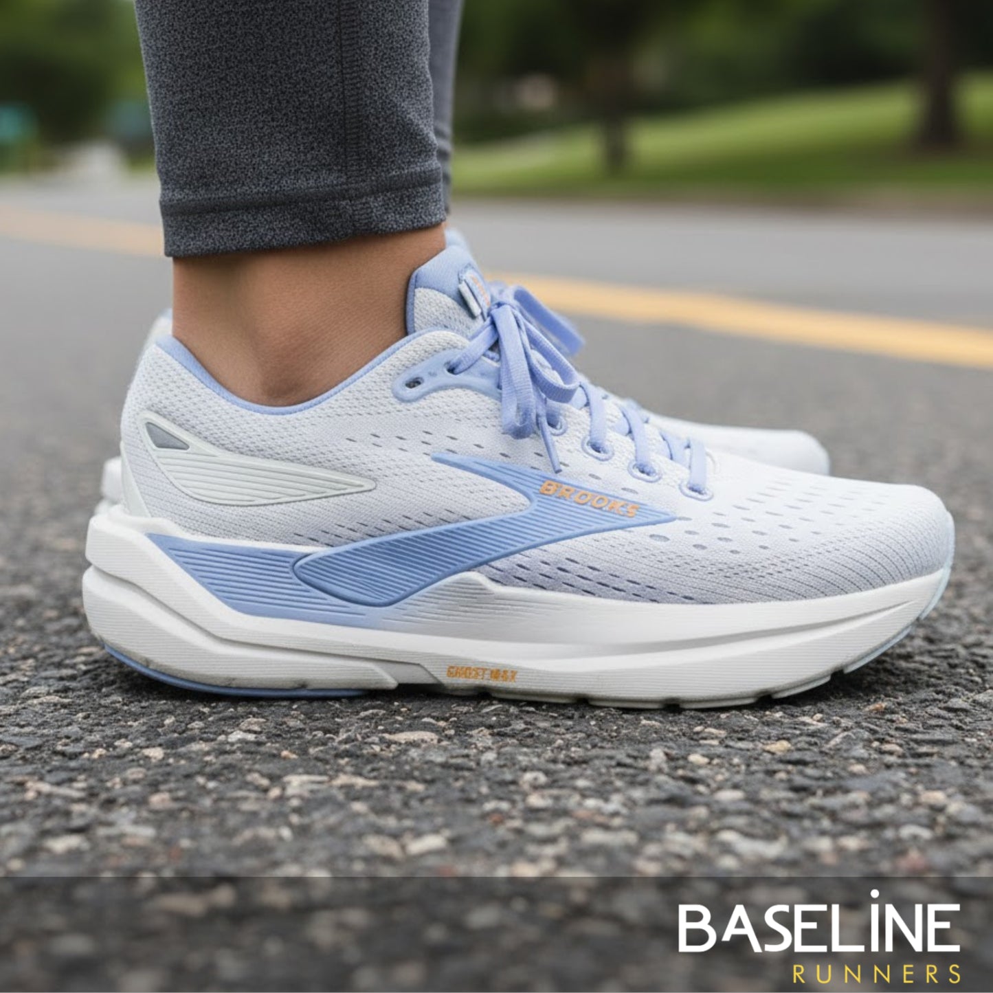 White and blue Brooks running shoes on a road with 'Baseline Runners' branding.