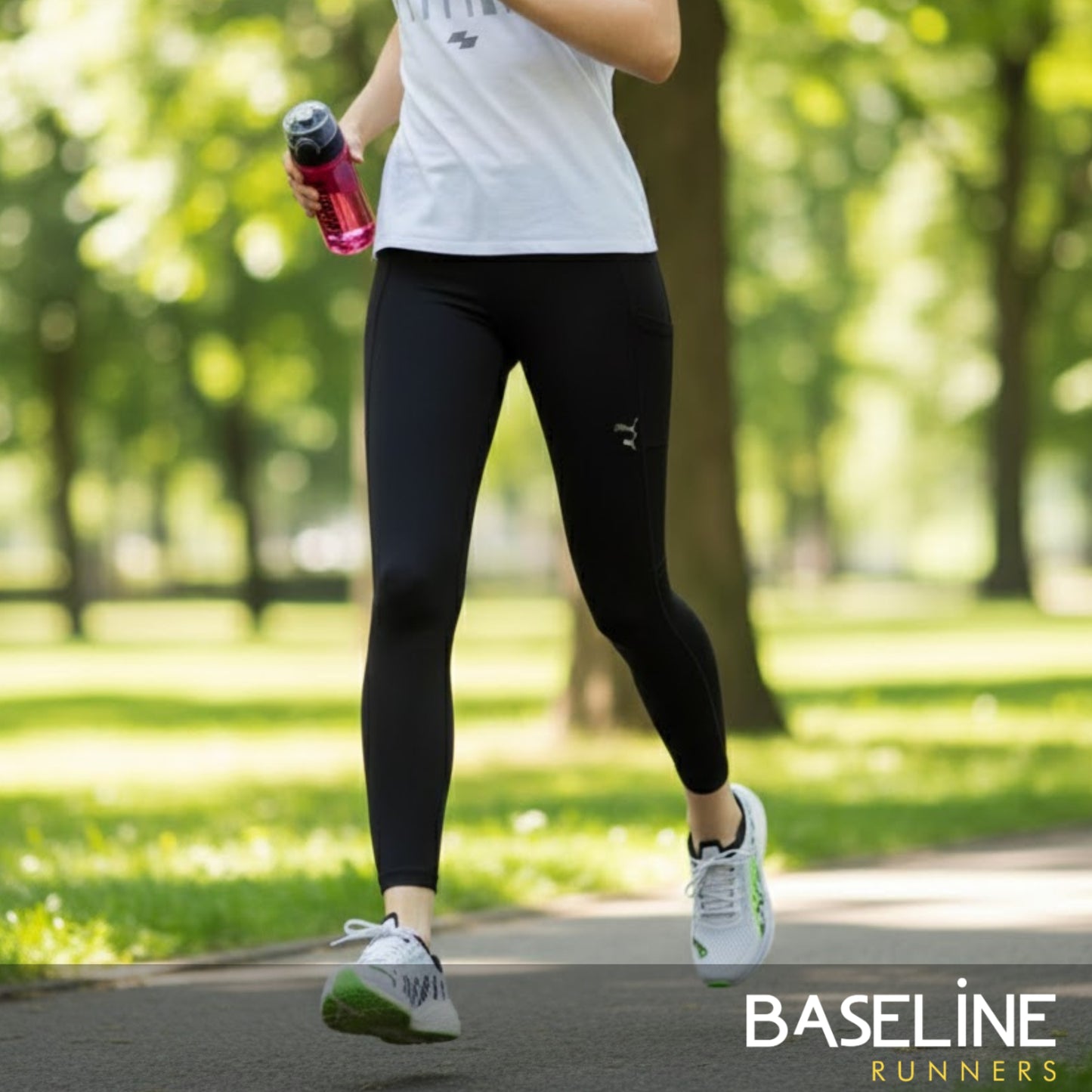 Person running outdoors holding a water bottle, wearing black leggings and white sneakers.