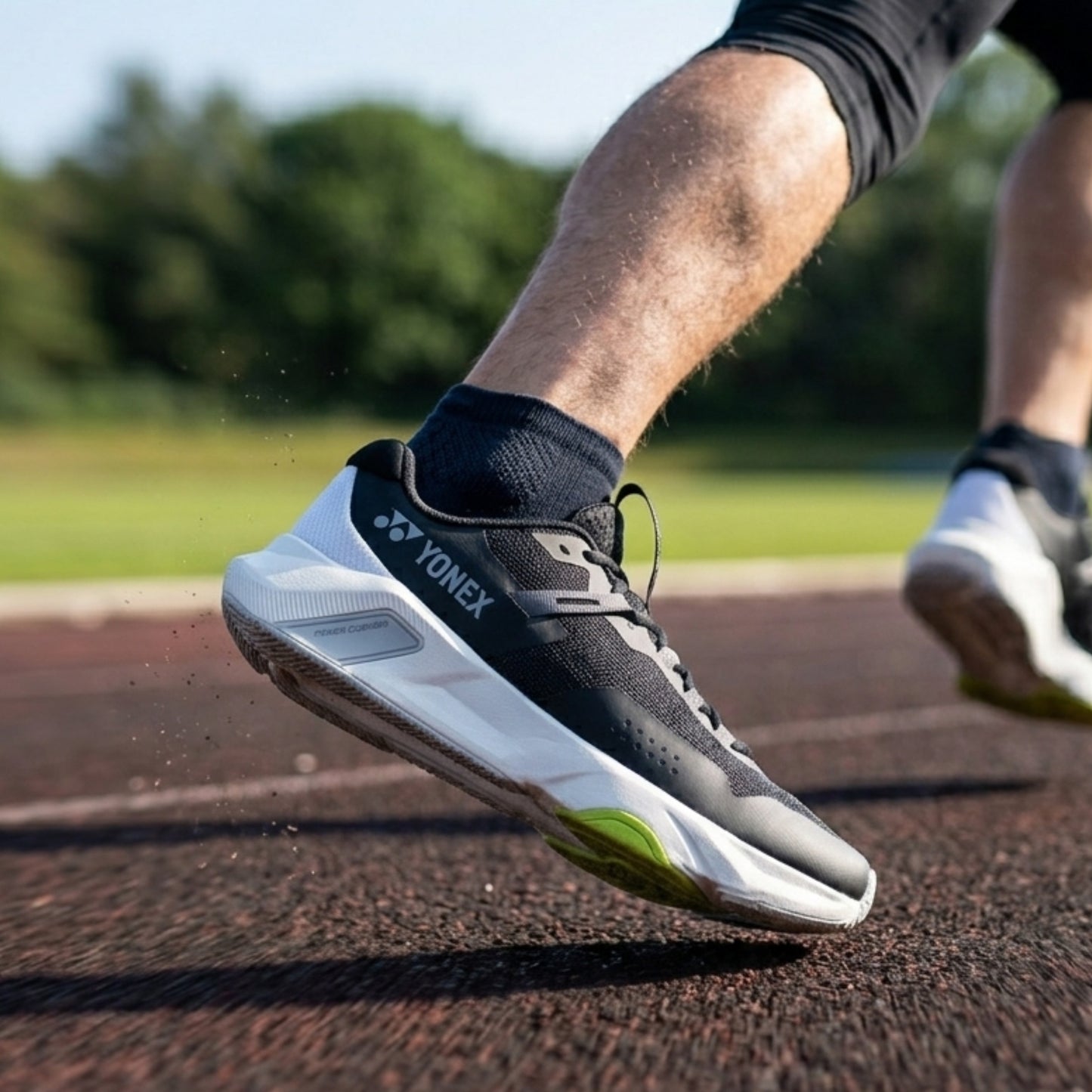 Person wearing Yonex running shoes on a track with blurred greenery in the background