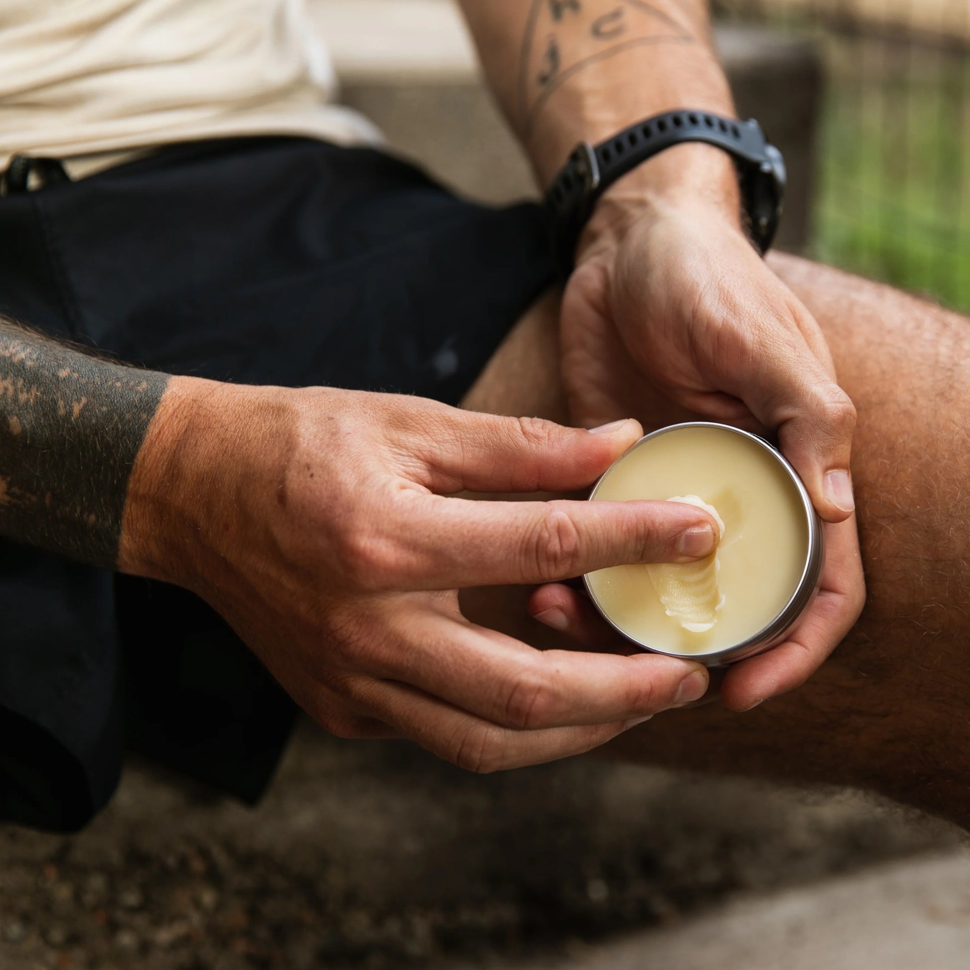 Person applying a cream from a small container outdoors