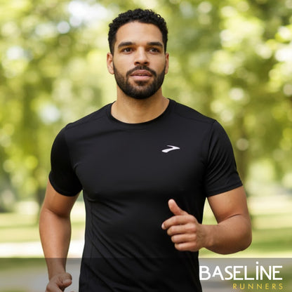 Man wearing a black athletic shirt with a brand logo, running outdoors.