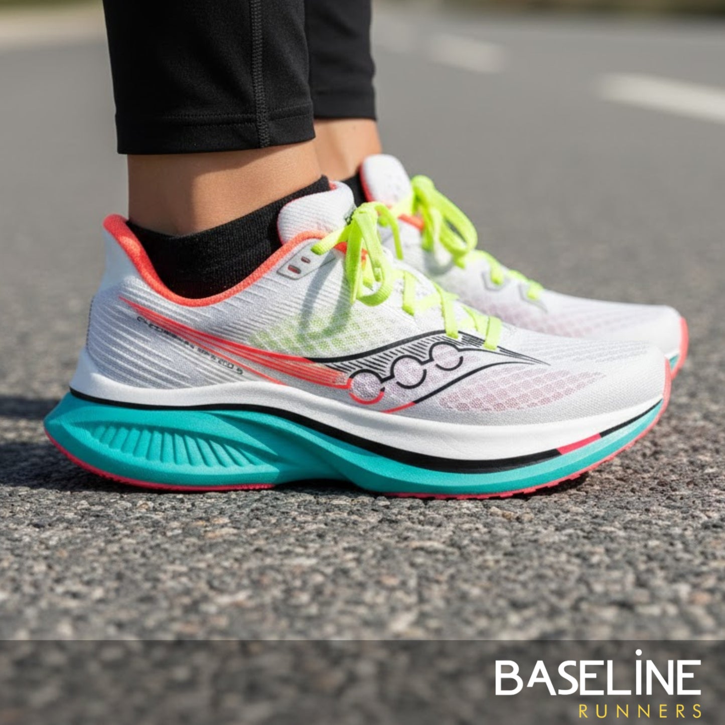 White running shoe with colorful sole on a road, featuring the Saucony brand.