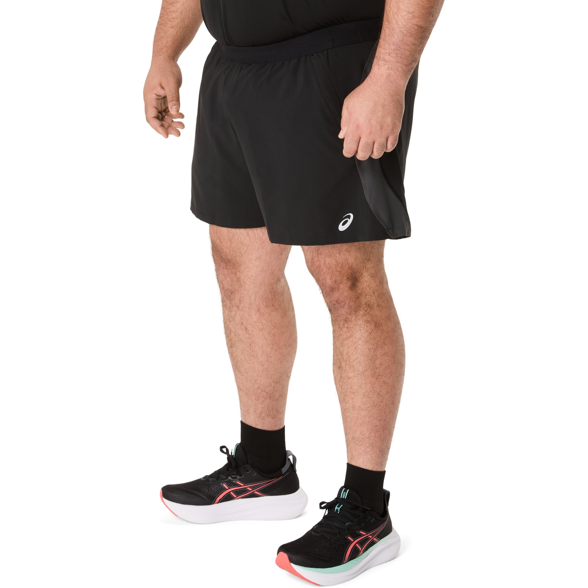 Person wearing black Asics running shorts and black running shoes with pink accents on a white background