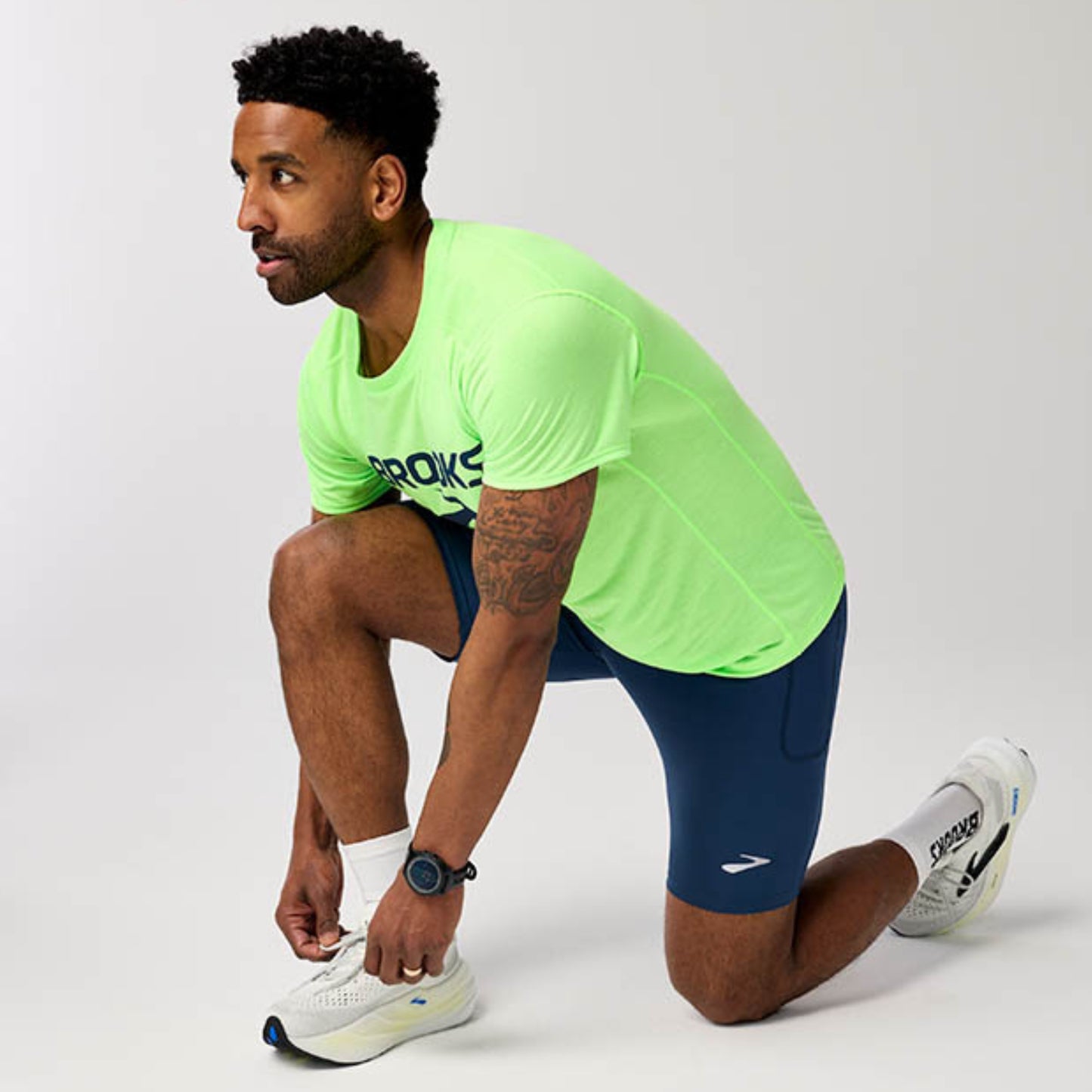 Man wearing a Brooks running shirt posing on a white background