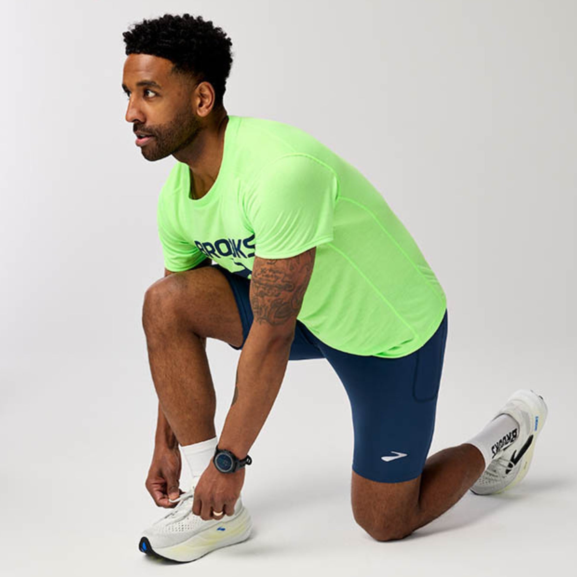 Man wearing a Brooks running shirt posing on a white background