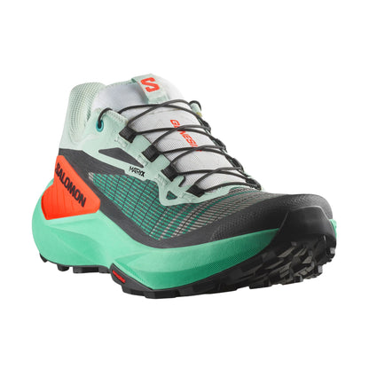 Green and black running shoe with orange accents on a white background