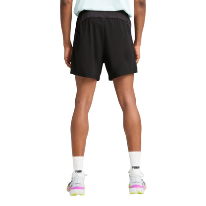 Person wearing black Puma shorts and white socks with a brand logo on a white background