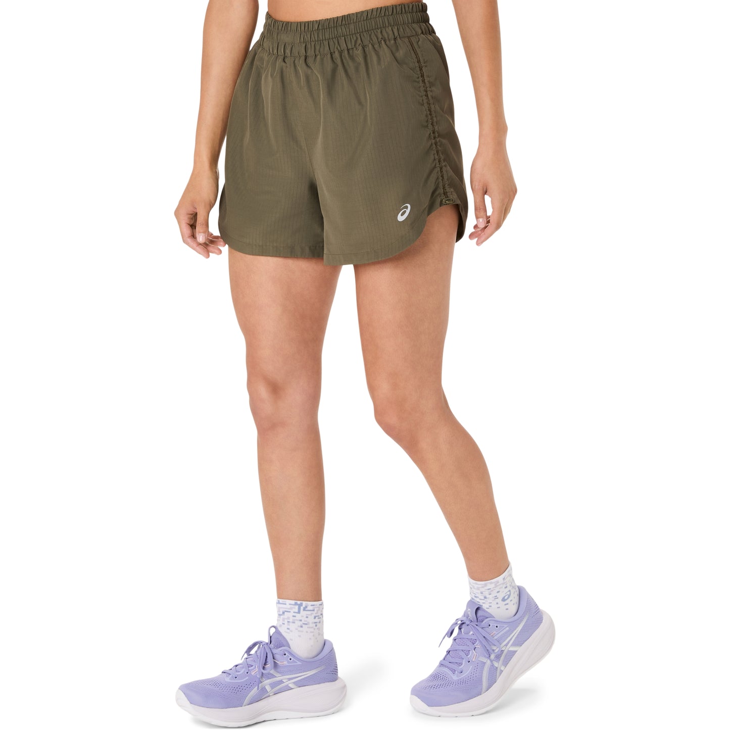 Person wearing olive green Asics shorts on a white background
