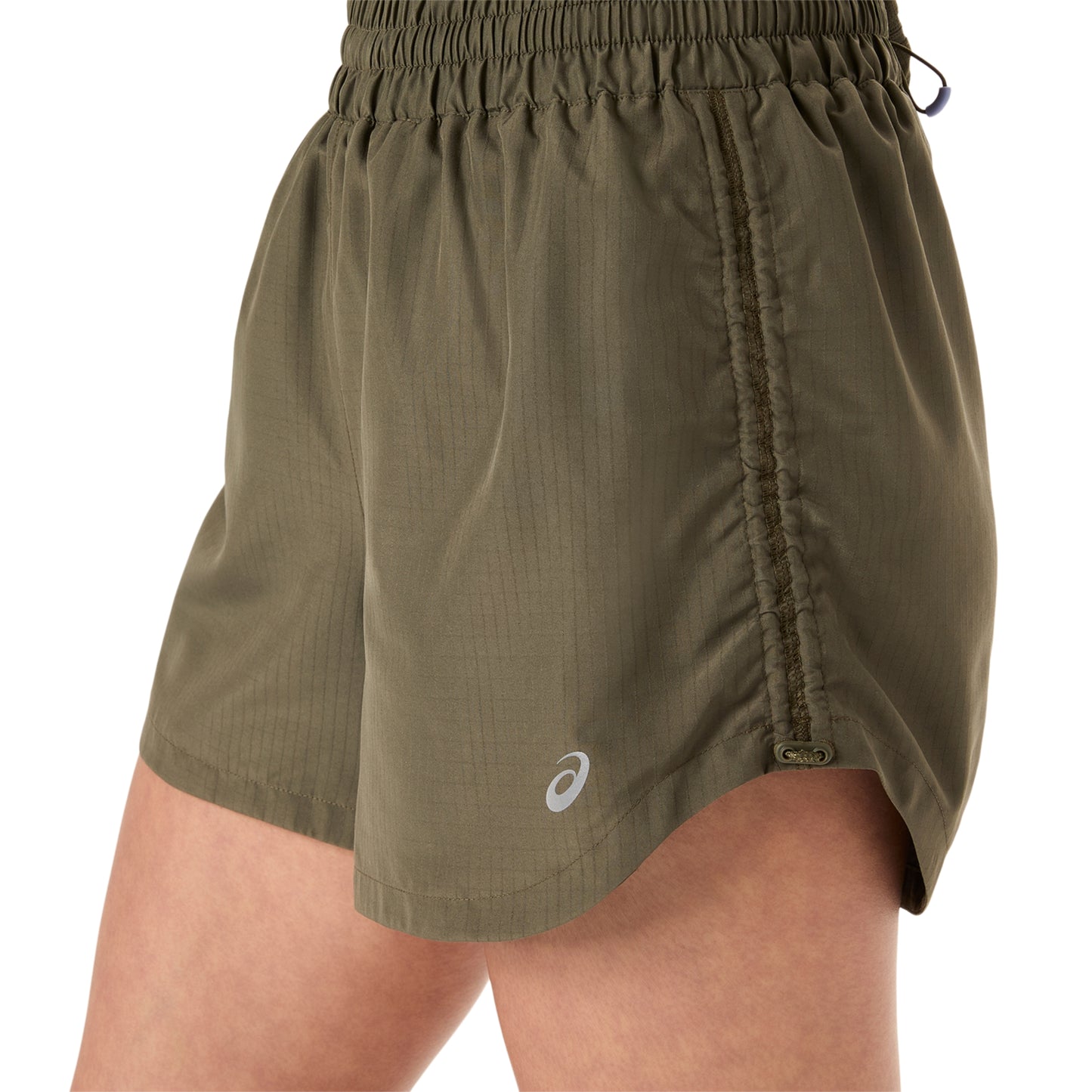 Person wearing olive green Asics shorts on a white background
