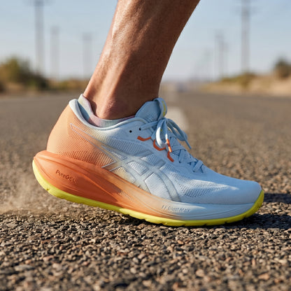 Person wearing white and orange Asics running shoe on a road background