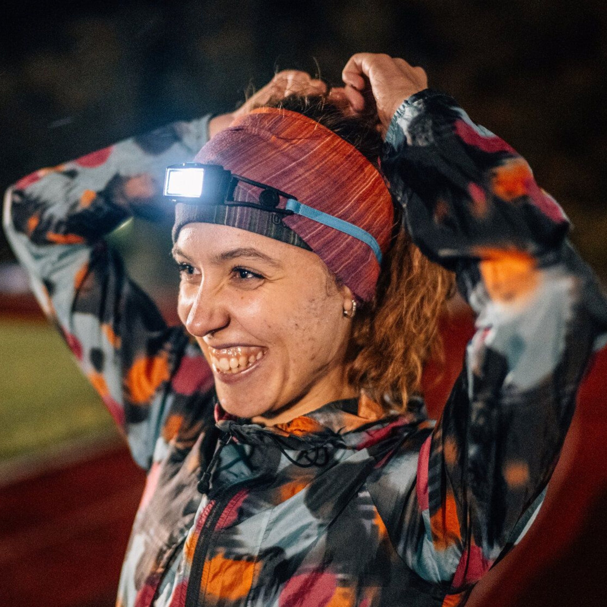 Person wearing a headlamp and colorful jacket outdoors