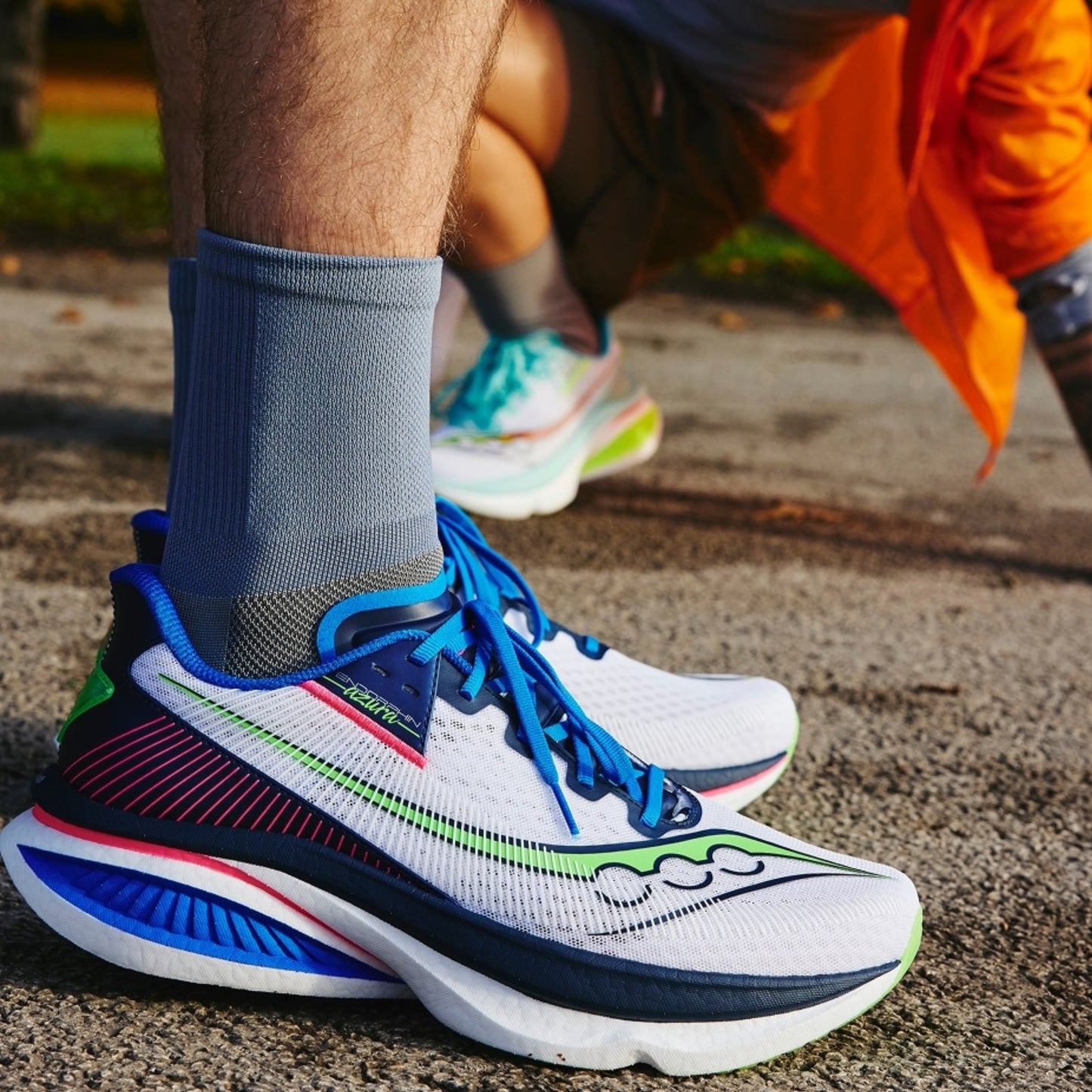 Close-up of a person wearing colorful Saucony running shoes on a road.