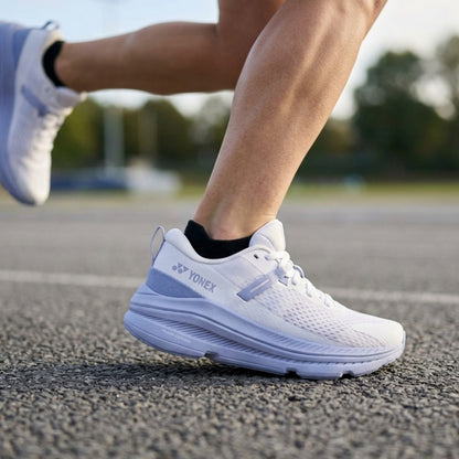 Person wearing white running shoes with Yonex logo on a track