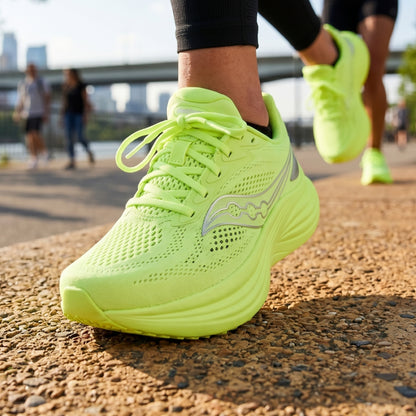 Nenon green Saucony running shoes with a visible brand logo on a road with people in the background.