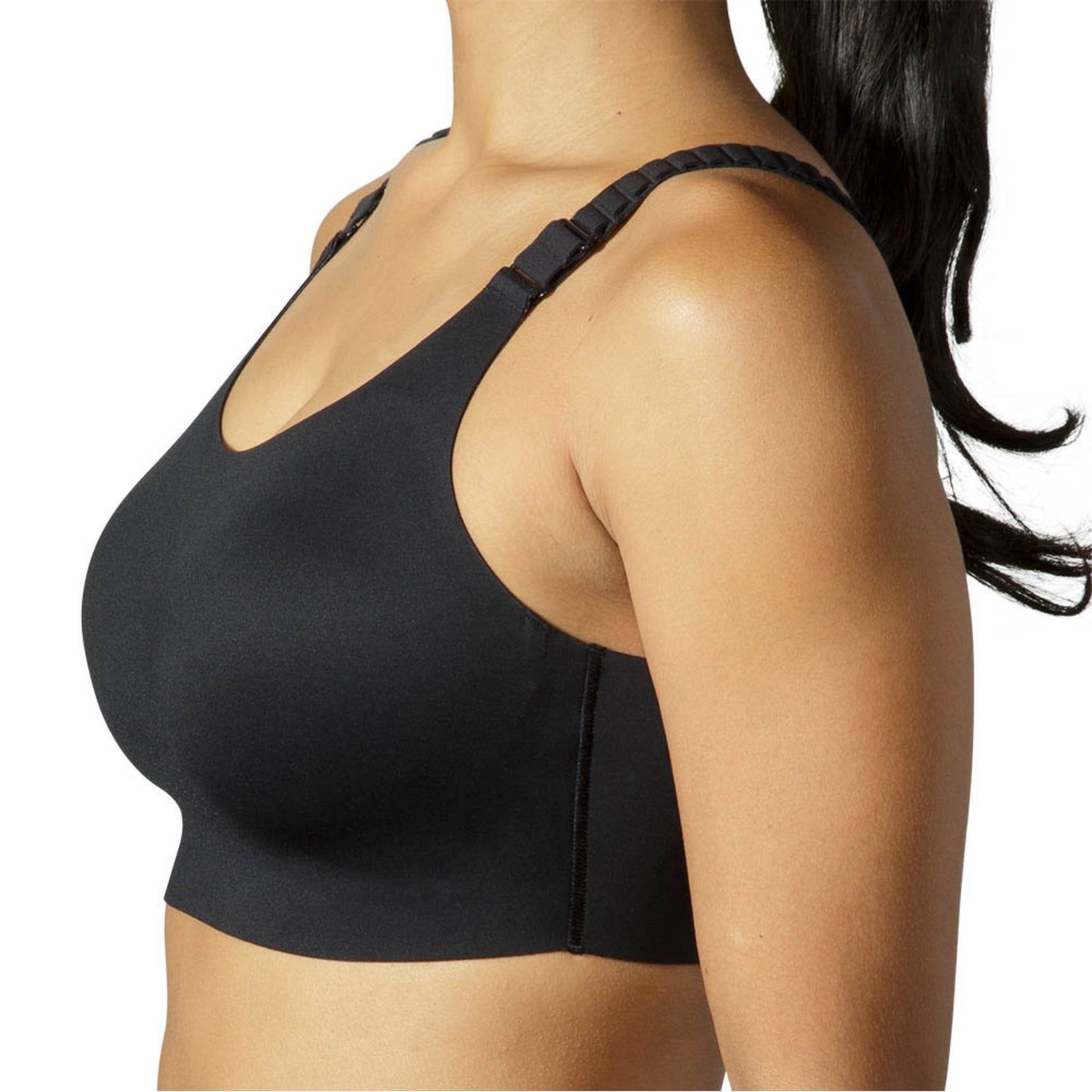 A close-up side view of a woman wearing a black wireless sports bra against a plain white background.