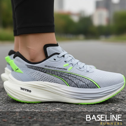 Gray Puma running shoe with green accents on a road, featuring the Puma brand.