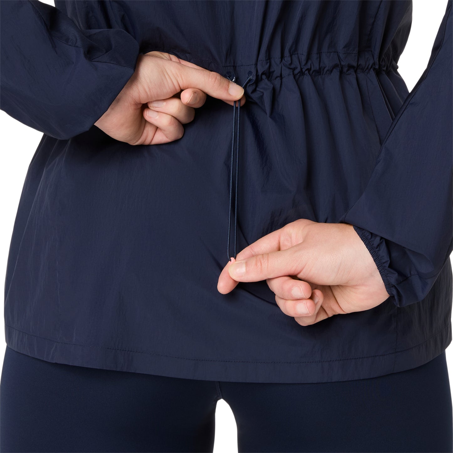 Person adjusting the waistband of a navy blue jacket on a white background