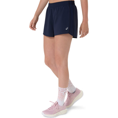 Person wearing navy Asics shorts with a brand logo on a white background