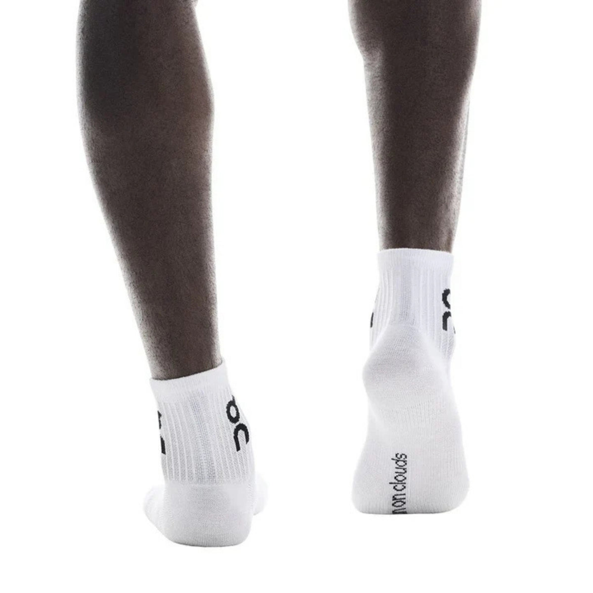 White low-cut athletic socks worn on a model's feet, shown from the back against a solid white background. The socks feature black printed branding and text.