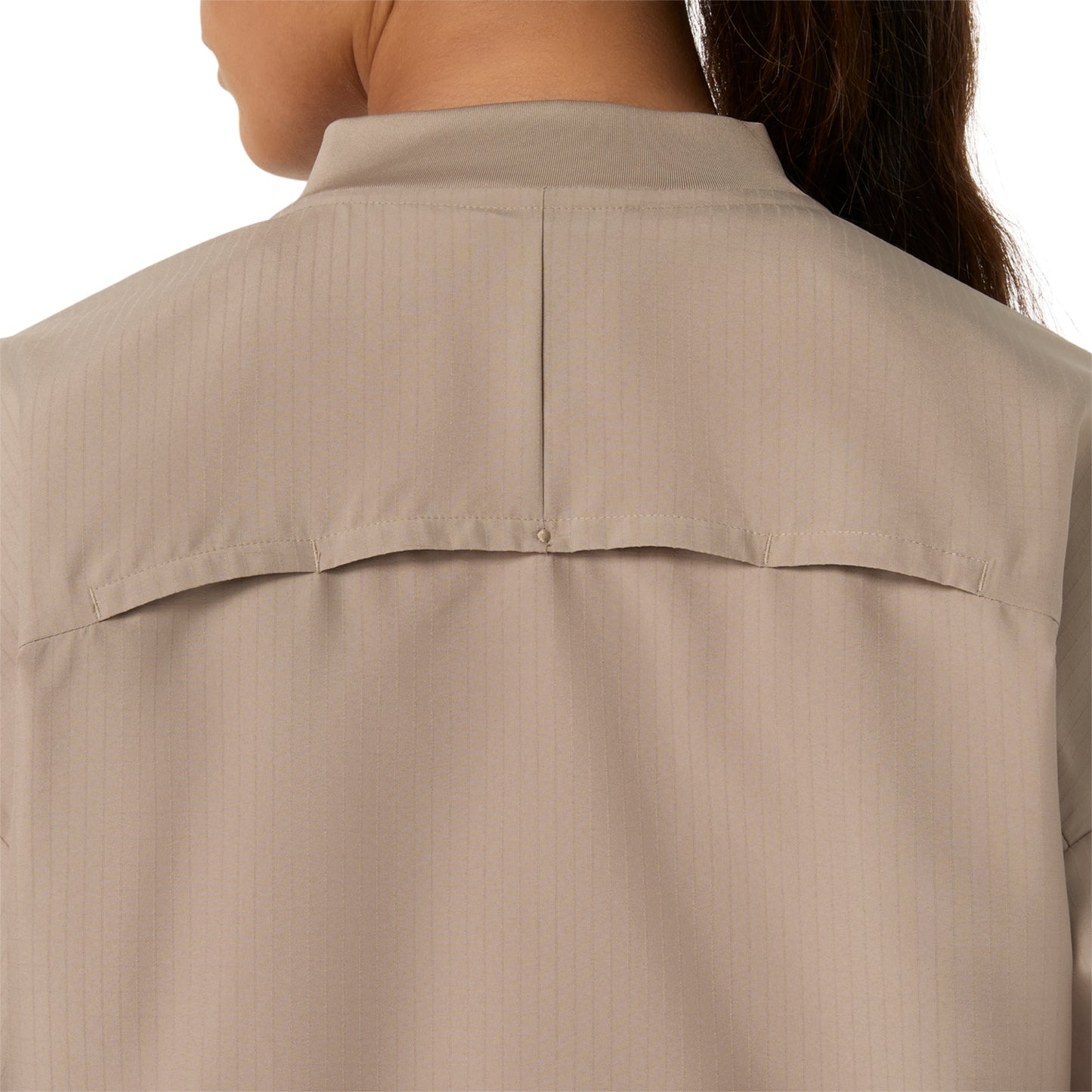 Close-up back view of a person wearing a light beige collared shirt with a buttoned chest seam and subtle vertical pinstripes.