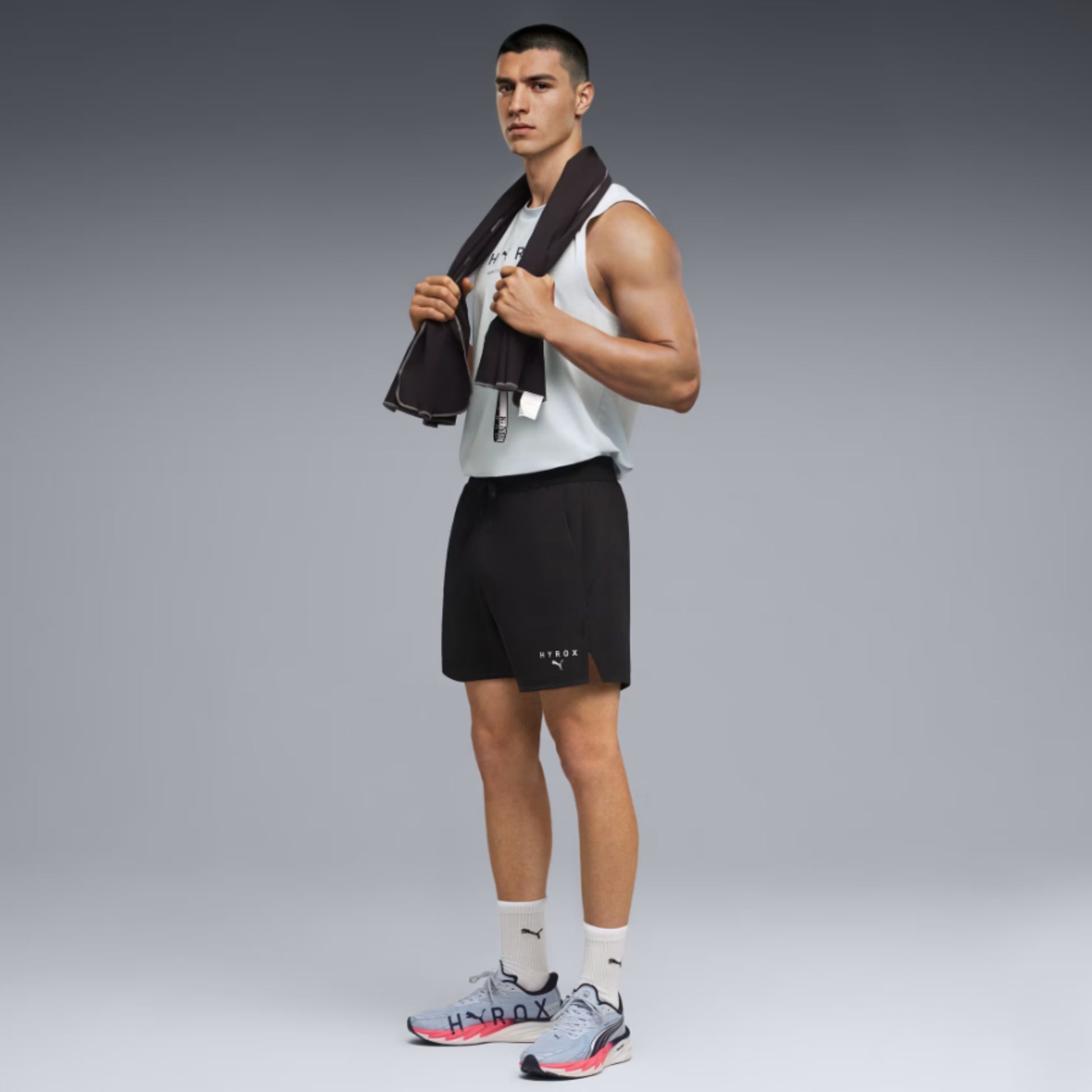 Man in athletic Puma wear holding a towel on a gray background