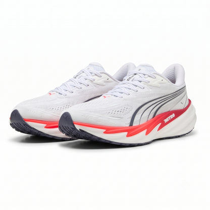 A pair of Puma running shoes in white, featuring a white mesh upper, a white and red midsole, and a dark gray outsole.
