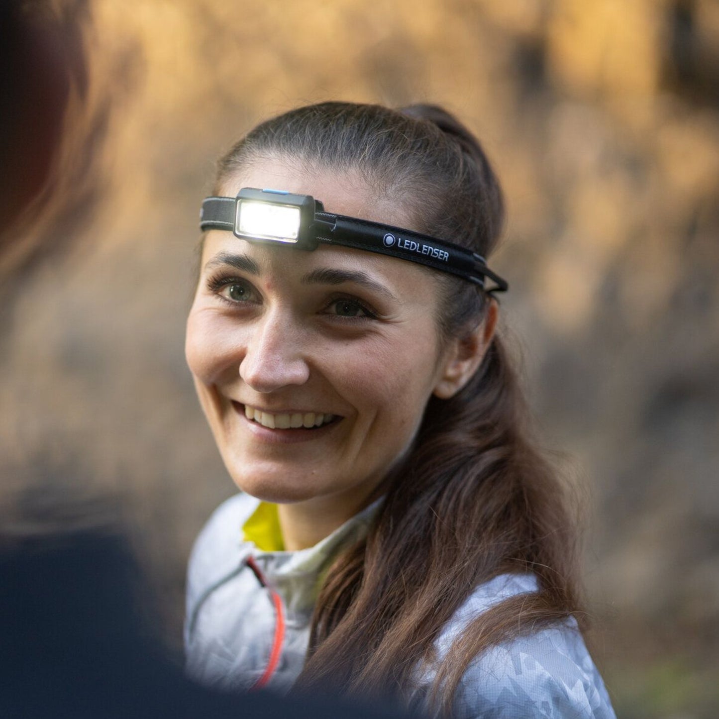 Woman wearing a headlamp in a forest setting