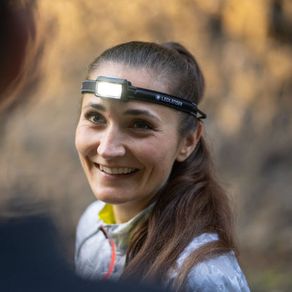 Woman wearing a headlamp in a forest setting