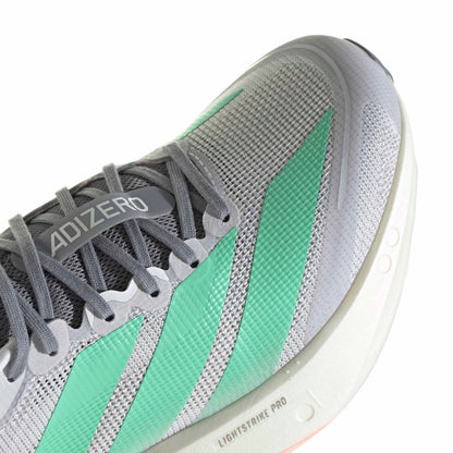 Close-up of an Adidas Adizero running shoe in gray and mint green, showing the textured mesh upper, gray laces, and part of the white Lightstrike Pro midsole.