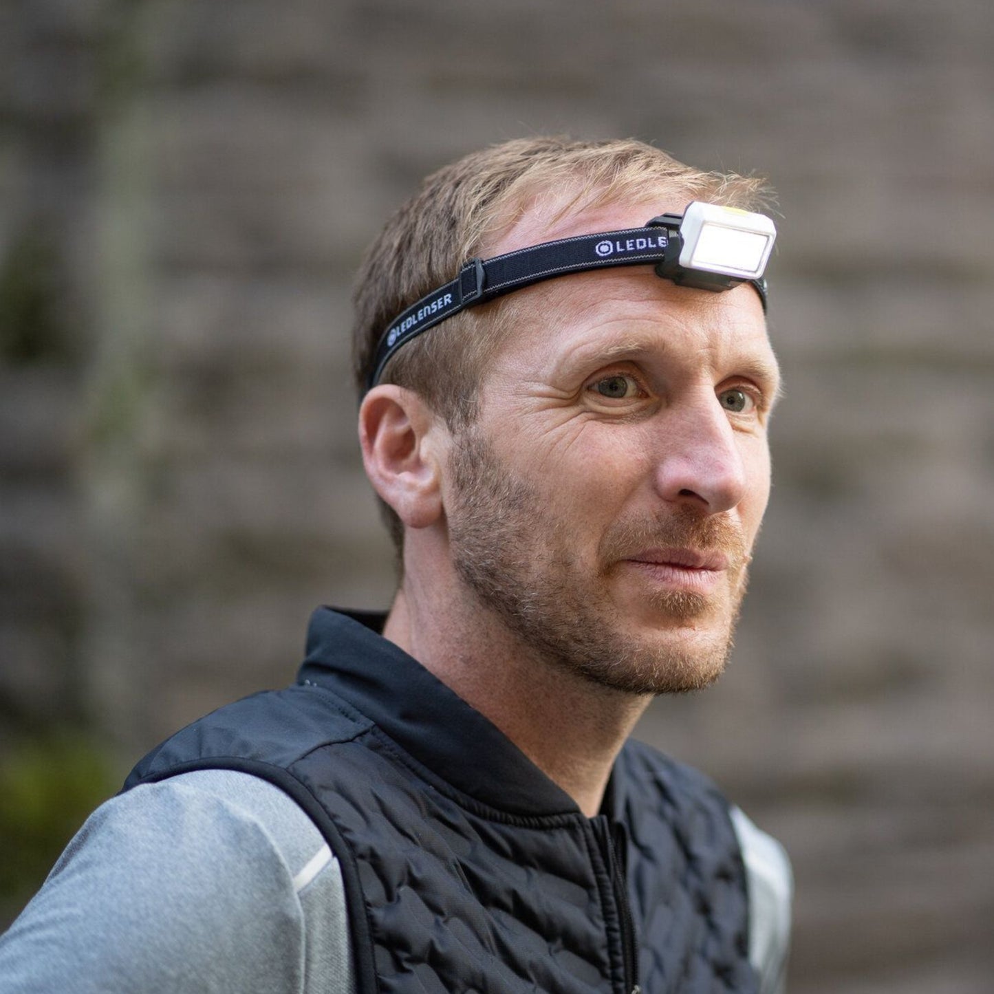 Man wearing a headlamp outdoors with a blurred background
