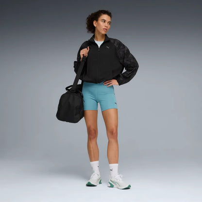 Woman in athletic wear holding a black bag on a gray background