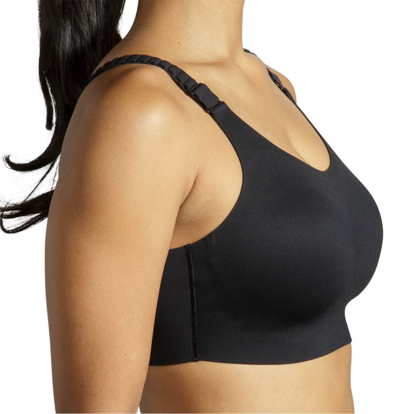 A close-up side view of a woman wearing a black wireless sports bra with wide adjustable shoulder straps against a plain white background.