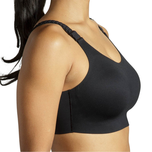 A close-up side view of a woman wearing a black wireless sports bra with wide adjustable shoulder straps against a plain white background.