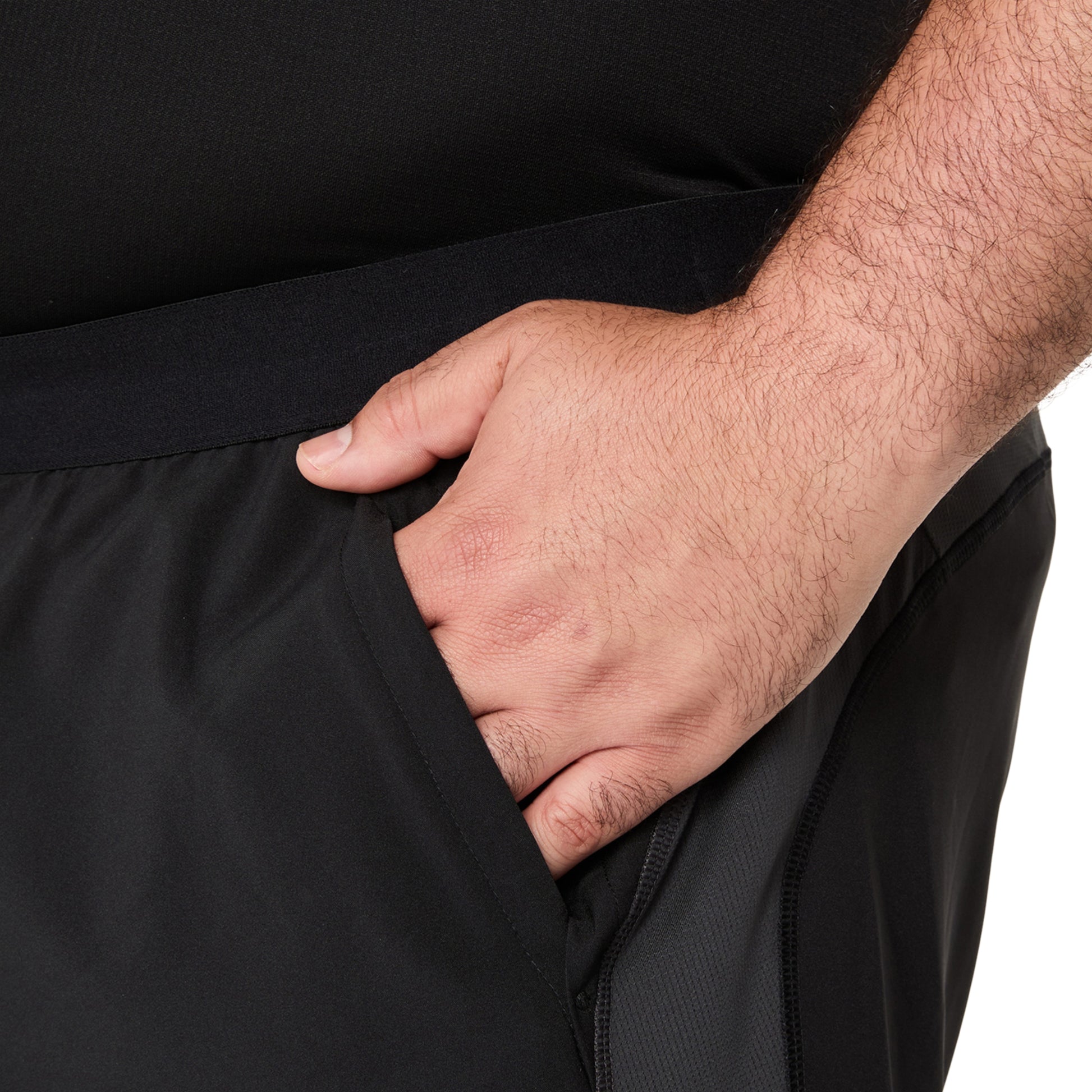 Person wearing black Asics running shorts with hand in the pockt on a white background