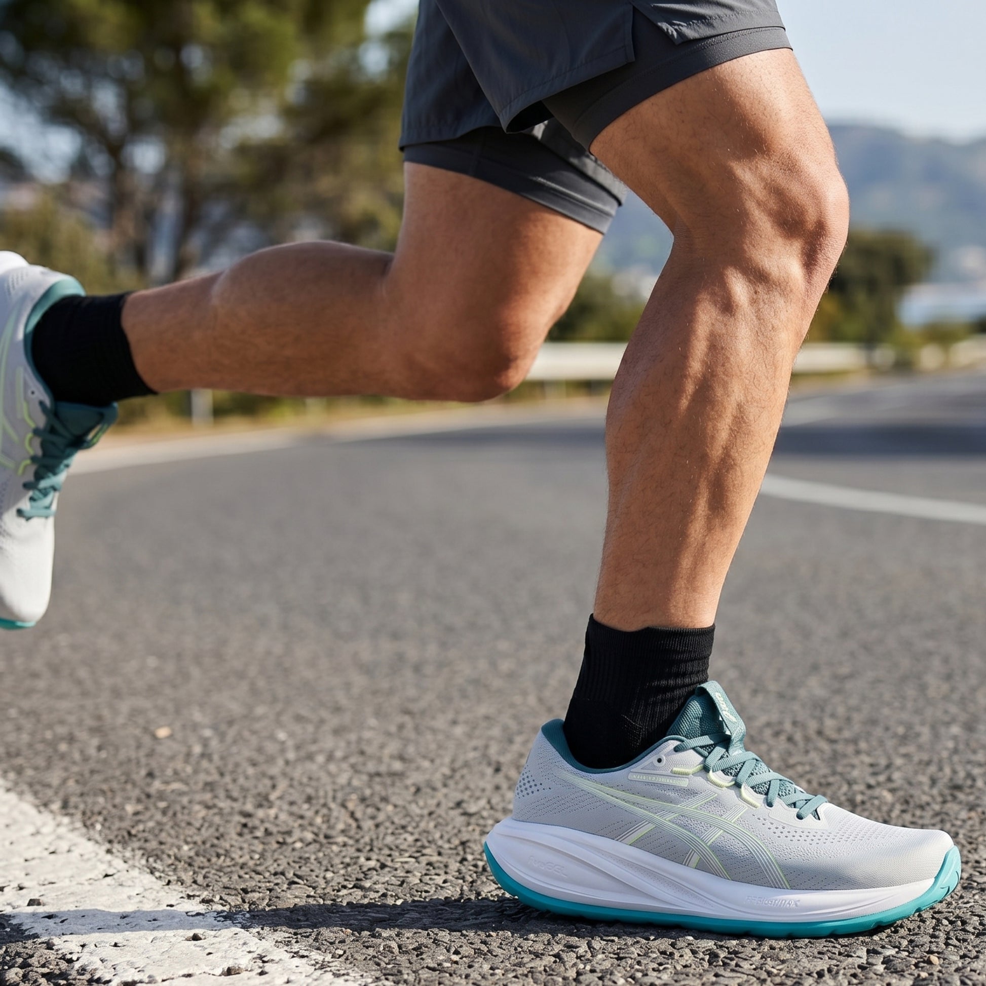 Person running on a road wearing light blue running shoes with green accents.