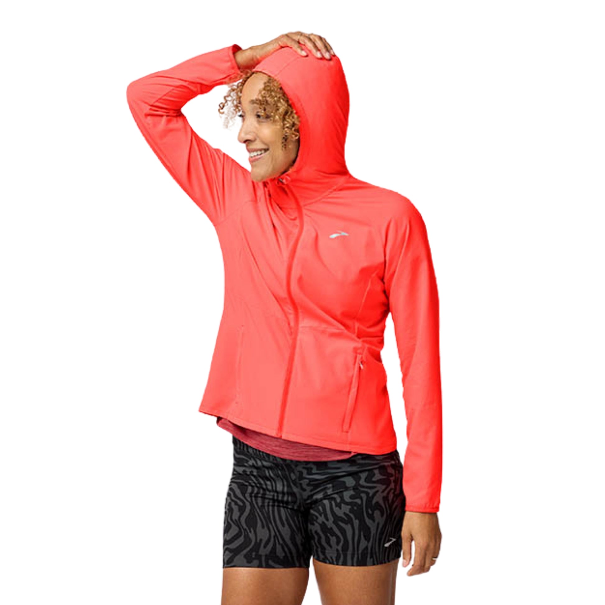 Woman wearing a orange jacket with a Brooks logo on a white background
