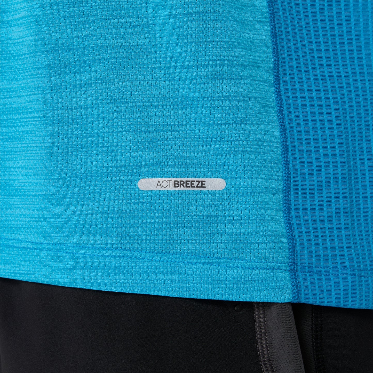 Close-up of a blue Asics shirt with 'ActiBreeze' label, part of a sports outfit.