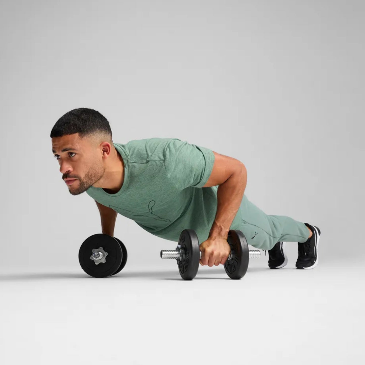 Man performing push-ups with black dumbbells on a light gray background