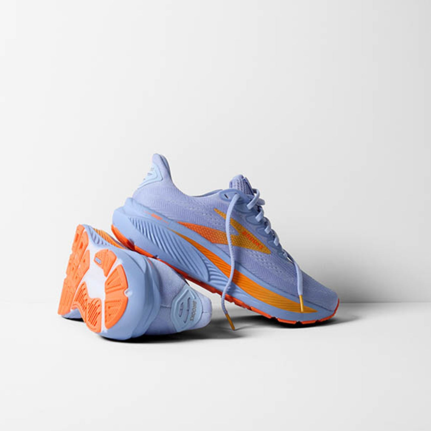 Pair of light blue running shoes with orange accents on a white background