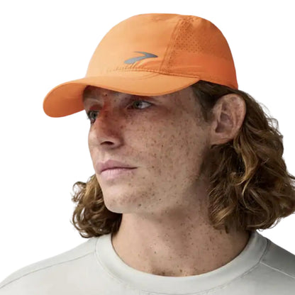 Man wearing a orange cap with a black Brooks logo on a white background