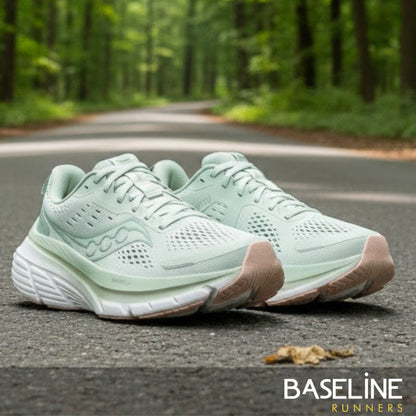 Pair of light green running shoes on a road with a forest background, featuring the 'Baseline Runners' brand.