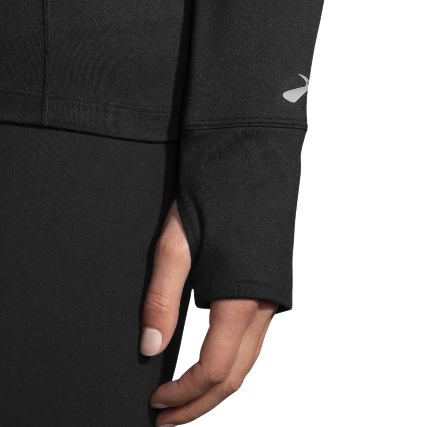 Close-up of a woman wearing a black Brooks jersey, focusing on the wrist with clothing peace over her thumb on a white background
